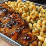 Honey Garlic Butter Chicken with Mac and Cheese in a glass meal-prep container, featuring juicy glazed chicken slices beside creamy macaroni.