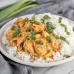 Crock pot Sweet Chili Chicken served over fluffy white rice, topped with sliced green onions for an easy creamy slow cooker dinner.