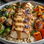 Maple Dijon Chicken Sweet Potato Bowls with sliced glazed chicken, roasted sweet potatoes, crispy Brussels sprouts, and brown rice in a bowl.