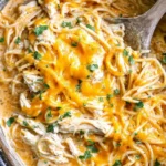 Creamy Crock Pot Chicken Spaghetti with shredded chicken, melted cheddar cheese, and herbs in a slow cooker.