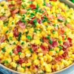 Bowl of creamy Crack Corn Salad topped with crispy bacon and fresh chives, ready to serve.