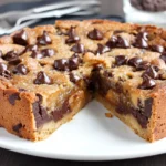 Deep Dish Cookie Pie baked thick with chocolate chips and golden edges on white plate