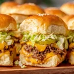 Easy Big Mac Sliders stacked with seasoned beef, melted cheese, pickles, lettuce, and sesame seed buns on a wooden board