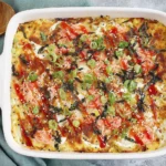 Easy Sushi Bake Recipe baked in a casserole dish with imitation crab, sushi rice, sriracha, mayo drizzle, sesame seeds, and green onions