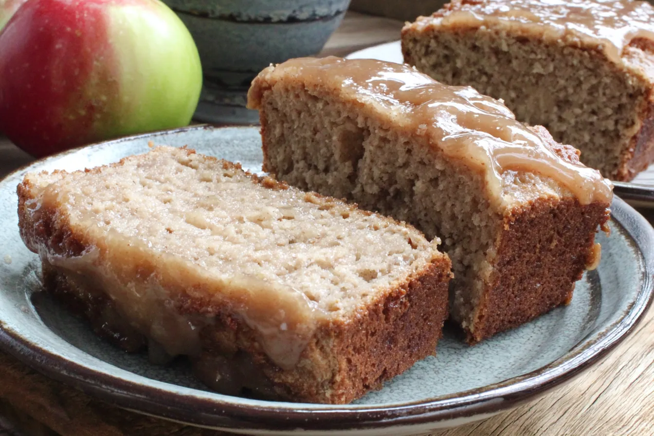Glazed Apple Cinnamon Oatmeal Bread slices on plate with fresh apple in background