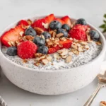 Greek Yogurt Chia Pudding topped with fresh strawberries, blueberries, and sliced almonds in a ceramic bowl