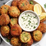 Homemade Falafel arranged on a platter with lemon and herb sauce