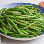 Miso Green Beans served in a blue bowl with sesame seeds and savory miso sauce