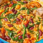 Mediterranean Orzo and Beans simmering in a pot with kidney beans, cherry tomatoes, carrots, and spinach in a cozy tomato-broth sauce.