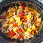 Slow Cooker Caribbean Jerk Chicken with shredded chicken, pineapple chunks, and bell peppers simmering in a crockpot.