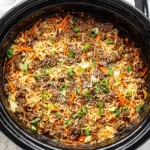 Slow Cooker Ramen Noodles with Ground Beef cooking in a crockpot with carrots, cabbage, and green onions