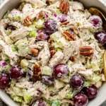 Sonoma Chicken Salad topped with red grapes and toasted pecans in a rustic bowl