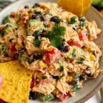 Southwestern Chicken Salad served with tortilla chips, black beans, corn, avocado, and cilantro on a plate