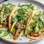 Teriyaki Chicken Tacos with Creamy Sesame Cucumbers and sesame seeds on a white plate