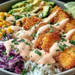 Crispy Fish Taco Bowls with golden panko-crusted fish, zesty purple cabbage slaw, sweet corn, avocado slices, and creamy chipotle lime sauce over rice.