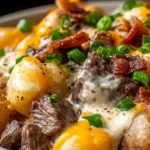 Crockpot Loaded Steak and Potato Bake topped with melted cheddar, crispy bacon, and green onions in a creamy sauce.