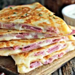 Corned Beef and Swiss Reuben Quesadillas on a wooden board with crispy tortillas, melted cheese, and dipping sauce