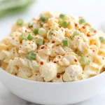 Deviled Egg Pasta Salad served in a white bowl with paprika and green onions