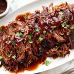Slow Cooker BBQ Beef Brisket served on a platter with rich barbecue sauce and fresh parsley