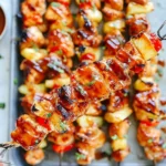 BBQ Pineapple Chicken Kabobs close-up on a skewer with glazed grilled chicken, caramelized pineapple, and peppers, with extra BBQ sauce for dipping.