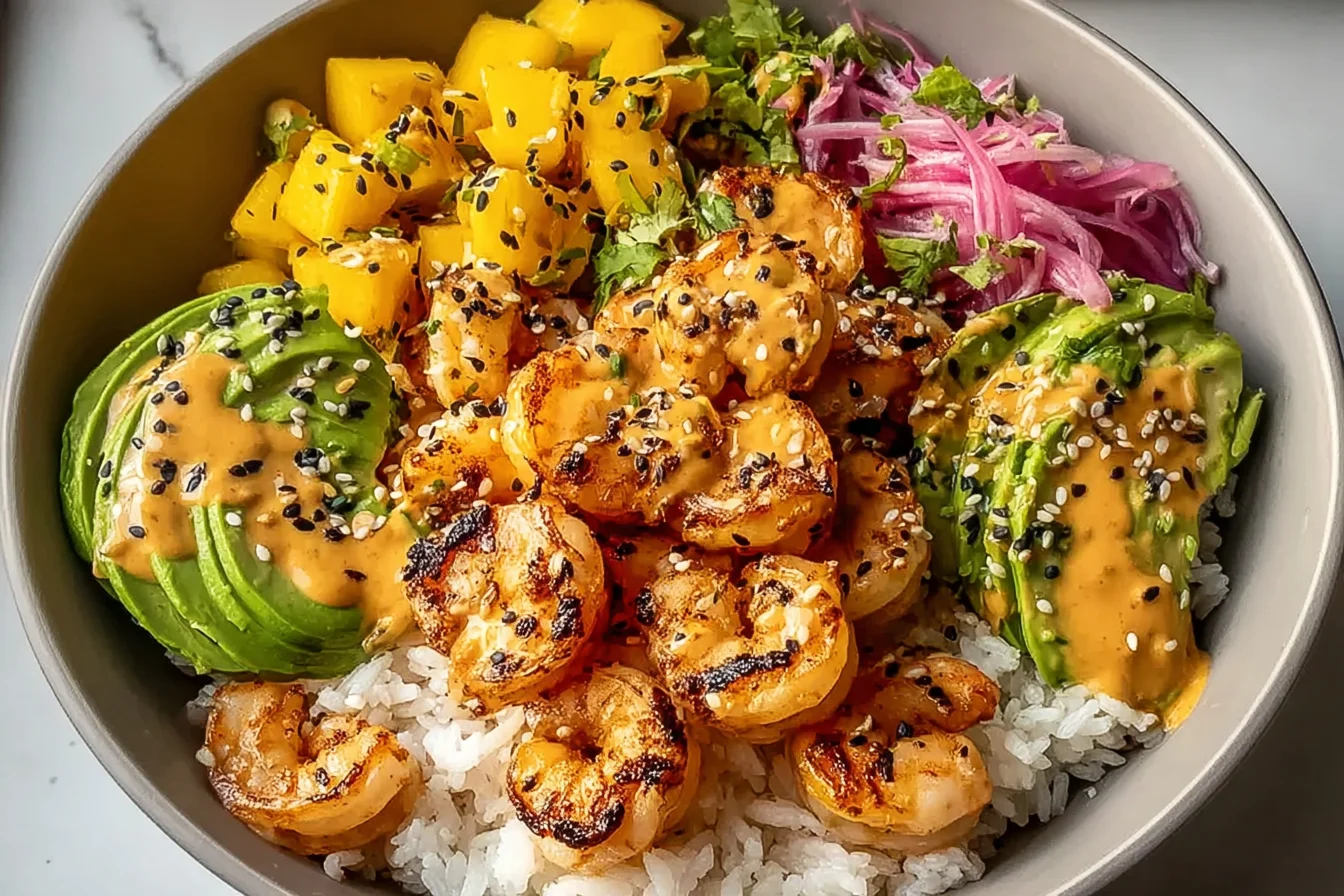 Shrimp and Avocado Bowl with charred chili shrimp, fluffy white rice, mango salsa, creamy avocado, and spicy lime drizzle topped with black sesame.