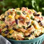 Mexican Coleslaw in a teal bowl—creamy cabbage slaw with black beans, charred corn, red pepper, cilantro, and lime dressing on a spoon.