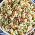 Creamy Pasta Salad in a large bowl with shell pasta, sweet peas, crispy bacon, and parmesan tossed in a creamy dressing.