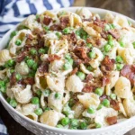 Creamy Pasta Salad with bacon, peas, and parmesan in a tangy creamy dressing, served in a white bowl.