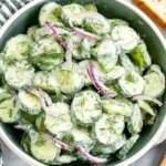 Top-down bowl of creamy Cucumber Dill Salad with sliced cucumbers, red onion, and fresh dill in yogurt dressing.