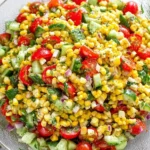 Bowl of Corn Salad with sweet corn, cherry tomatoes, diced cucumber, red onion, and fresh herbs tossed in a zesty lime dressing.