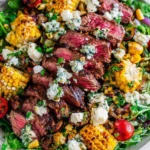 Balsamic Steak Gorgonzola Salad with Grilled Corn topped with sliced grilled sirloin, cherry tomatoes, spring greens, endive, and crumbled Gorgonzola.
