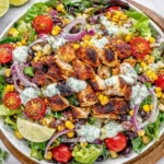 Mexican Grilled Chicken Salad in a bowl with grilled chicken, romaine, black beans, corn, cherry tomatoes, red onion, and creamy avocado dressing.