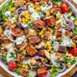 Mexican Grilled Chicken Salad with black beans, corn, tomatoes, red onion, and creamy avocado cilantro dressing in a large bowl.
