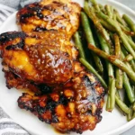 Grilled Honey Mustard Chicken with Green Beans plated with sticky honey mustard-glazed chicken thighs and tender green beans on a white dish.