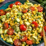 Summer Corn Salad with Avocado in a blue bowl with cherry tomatoes, cilantro, red onion, and fresh lime.