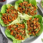 Thai Chicken Lettuce Wraps served in butter lettuce cups with sweet chili ground chicken, shredded carrots, cashews, cilantro, and scallions.