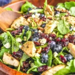 Close-up of Chicken Blueberry Feta Salad with grilled chicken, fresh spinach/spring greens, blueberries, dried cranberries, feta crumbles, and balsamic dressing.