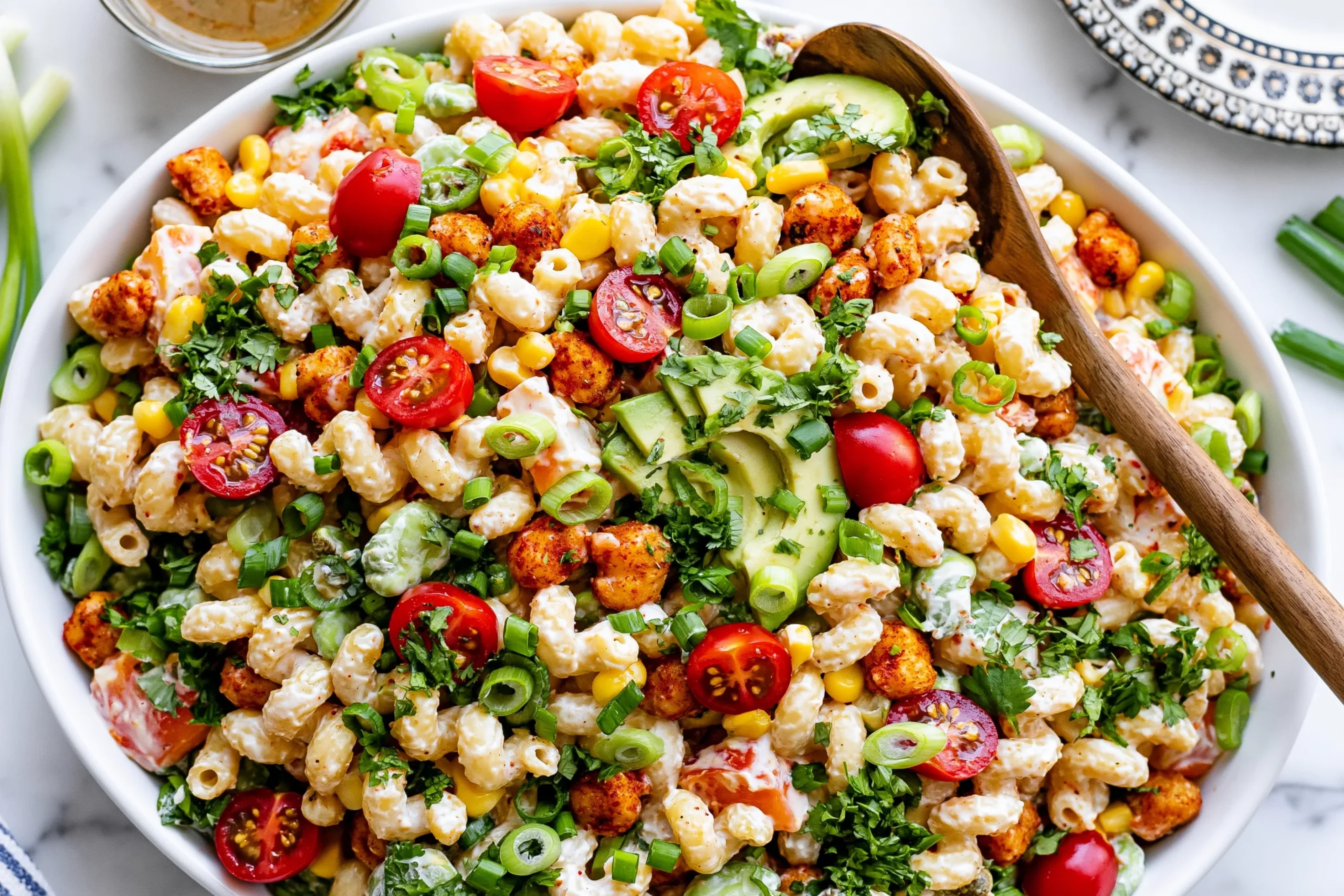 Buffalo Chickpea Pasta Salad in a large bowl with creamy ranch pasta, crispy buffalo chickpeas, cherry tomatoes, corn, avocado, cilantro, and green onions.