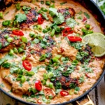 Coconut Chicken skillet with creamy coconut sauce, lime, cilantro, green onions, red chili slices, and rice on the side