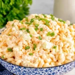 Creamy Macaroni Hawaiian Salad in a blue bowl topped with sliced green onions, made with elbow pasta, grated carrots, and a mayo dressing.