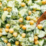 Rudy’s Sunshine Salad with chickpeas, cucumbers, and creamy tahini-lime dressing in a white bowl