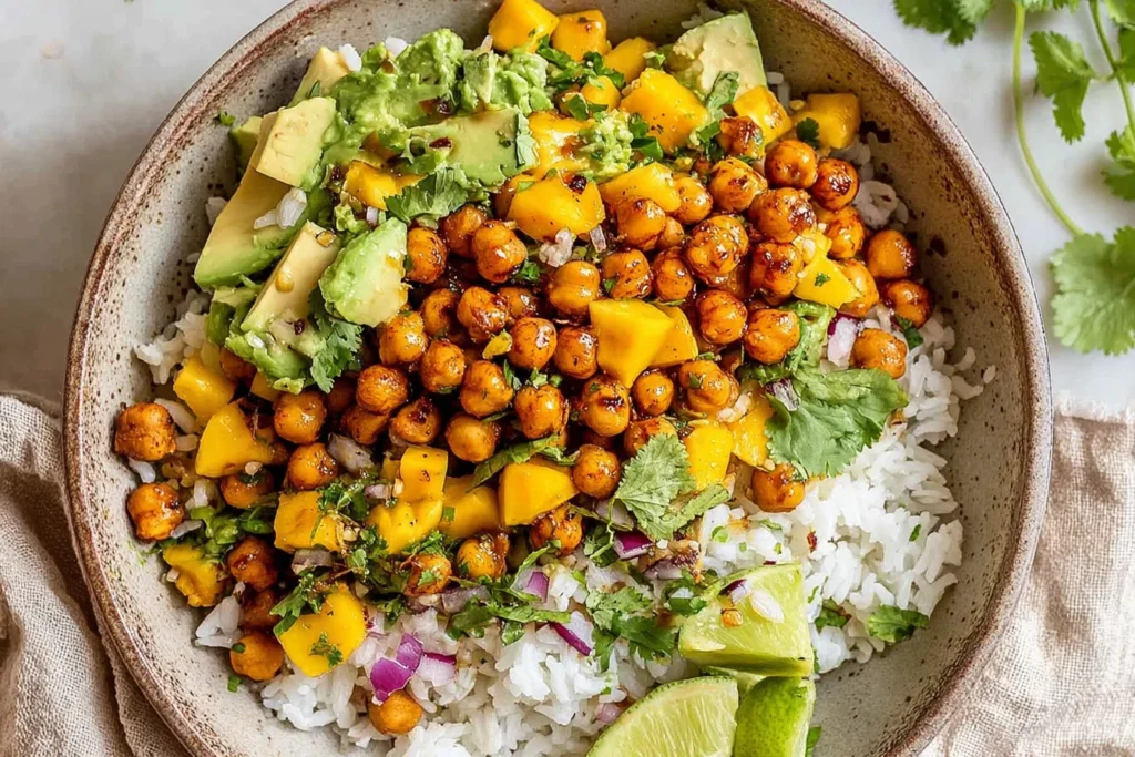 Overhead bowl of Mango Chickpea Salad with crispy roasted chickpeas, fluffy white rice, diced mango, creamy avocado, red onion, cilantro, and lime drizzle.