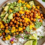 Overhead bowl of Mango Chickpea Salad with crispy roasted chickpeas, fluffy white rice, diced mango, creamy avocado, red onion, cilantro, and lime drizzle.