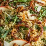 Close-up of Honey Mustard Quinoa Apple Salad with arugula, crisp apple slices, parmesan shavings, and crispy shallots tossed in honey mustard dressing.