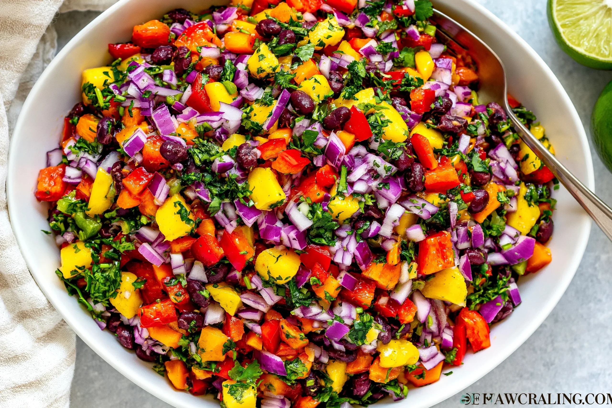 Black Bean Mango Salad with black beans, diced mango, red onion, bell pepper, cilantro, and lime in a white serving bowl
