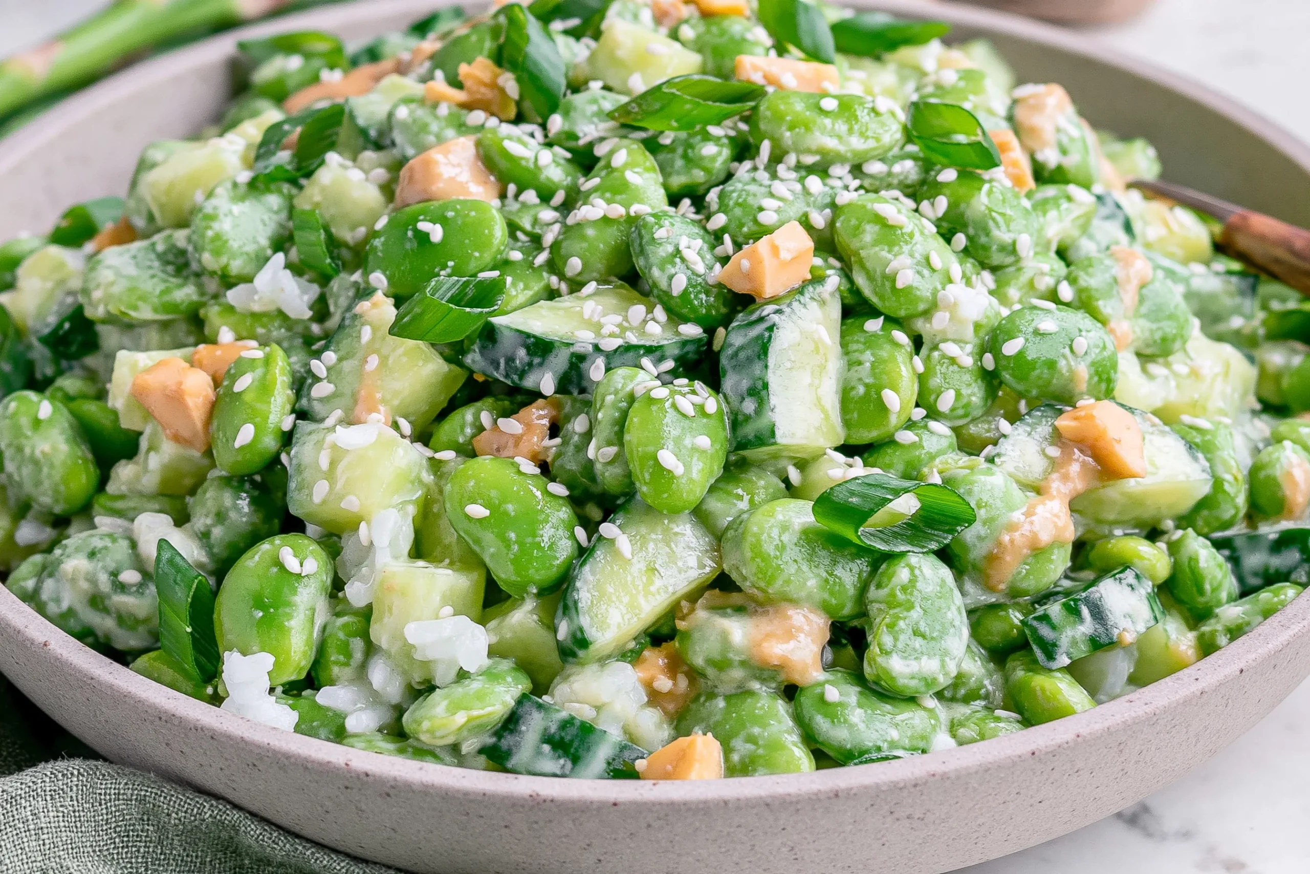 Cucumber Edamame Salad with creamy miso dressing, chopped cucumbers, edamame, cashews, sesame seeds, and green onions in a bowl