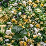 Mexican Street Corn Kale Salad with avocado, cotija cheese, corn, cilantro, jalapeño slices, and lime in a bowl