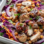 Sesame Chicken and Chickpea Salad with juicy chicken, chickpeas, red cabbage, carrots, green onions, and sesame seeds in a serving dish