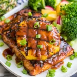 Hawaiian Grilled Salmon with grilled pineapple, sticky brown sugar glaze, scallions, broccoli, cucumber, and fresh pineapple on a plate