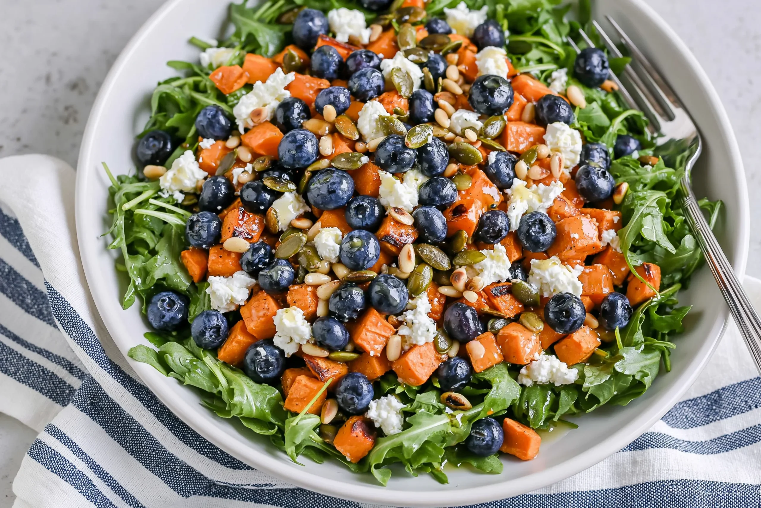 Honey Sweet Potato Summer Salad with roasted sweet potatoes, blueberries, arugula, goat cheese, pepitas, and pine nuts with honey lemon vinaigrette.